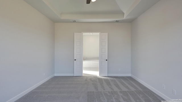 carpeted empty room with a tray ceiling