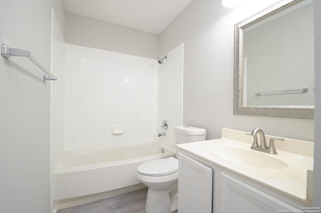 full bathroom with hardwood / wood-style flooring, vanity, tiled shower / bath combo, and toilet