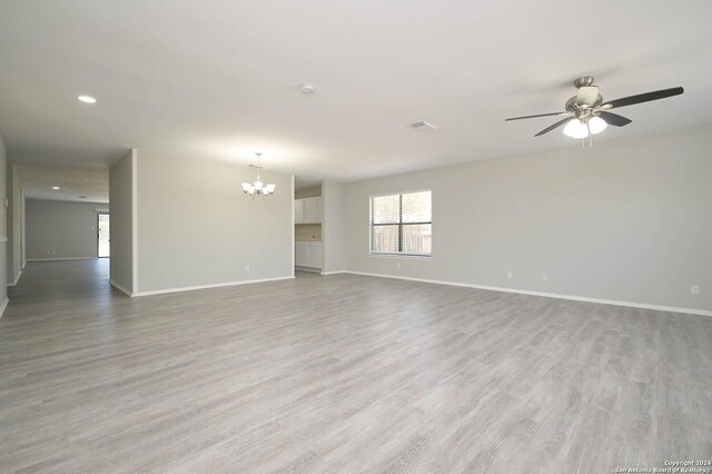 spare room featuring ceiling fan with notable chandelier and hardwood / wood-style floors