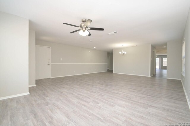 empty room with ceiling fan with notable chandelier and light hardwood / wood-style floors