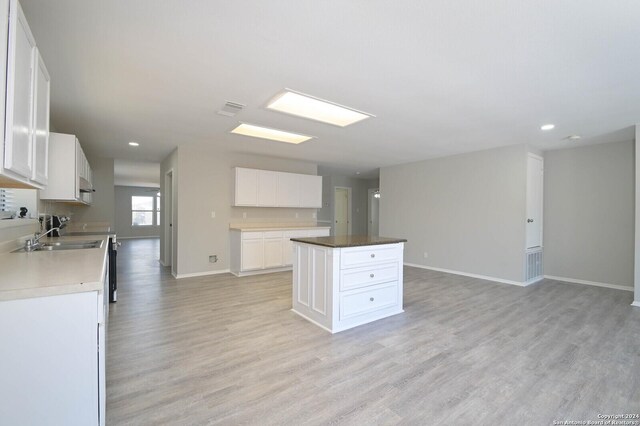 kitchen with a kitchen island, light hardwood / wood-style flooring, white cabinetry, and sink