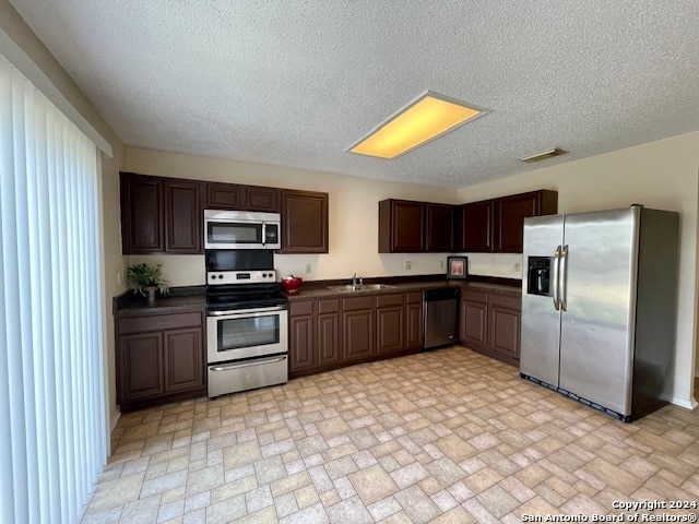 kitchen with a textured ceiling, sink, dark brown cabinetry, and stainless steel appliances