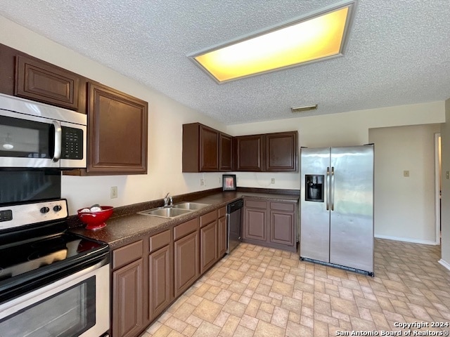 kitchen featuring stainless steel appliances, a textured ceiling, sink, and dark brown cabinetry