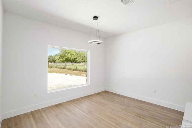 unfurnished room with light hardwood / wood-style floors and a textured ceiling