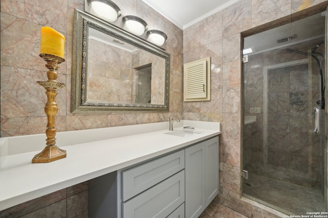 bathroom with tile patterned floors, vanity, tile walls, crown molding, and a shower with door