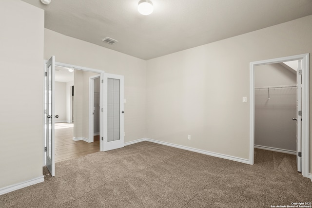 unfurnished bedroom featuring a walk in closet, a closet, and carpet floors