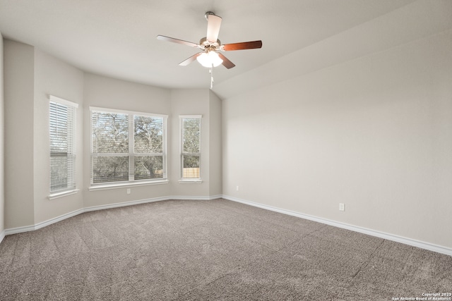 carpeted spare room with ceiling fan and vaulted ceiling