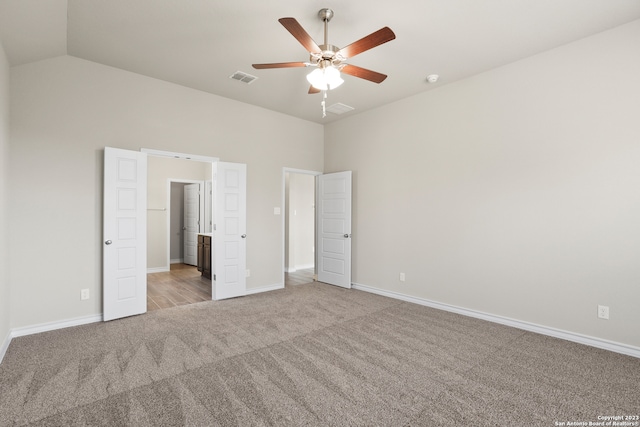 unfurnished bedroom featuring light carpet, ceiling fan, and vaulted ceiling