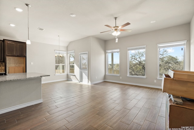 unfurnished living room featuring ceiling fan with notable chandelier