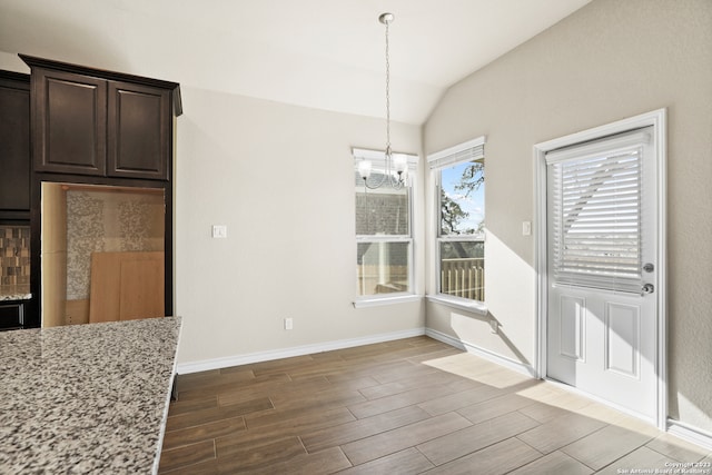 unfurnished dining area with lofted ceiling and a chandelier