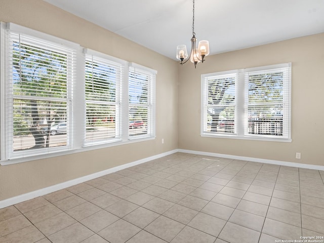 tiled spare room featuring a notable chandelier