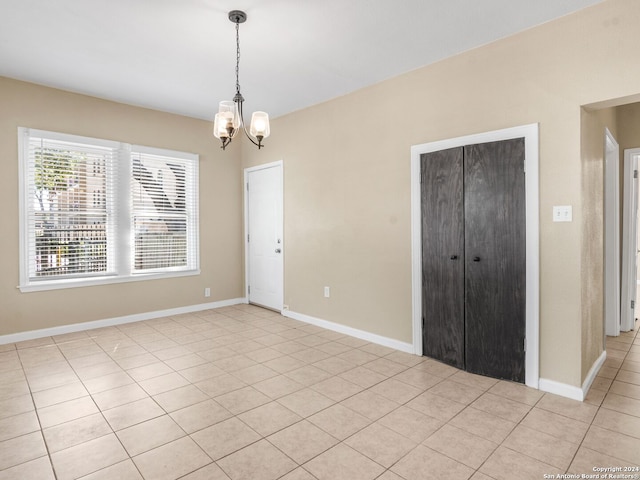 unfurnished bedroom featuring a closet, a notable chandelier, and light tile patterned flooring