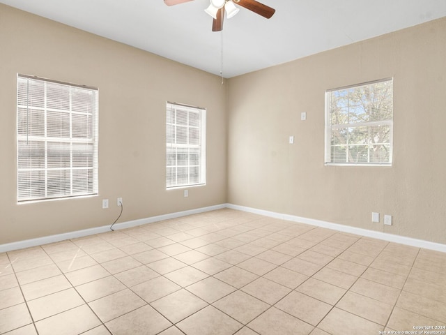 tiled spare room featuring ceiling fan and a wealth of natural light