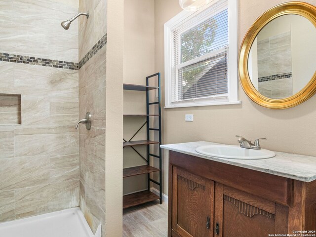 bathroom with tiled shower, vanity, and hardwood / wood-style floors