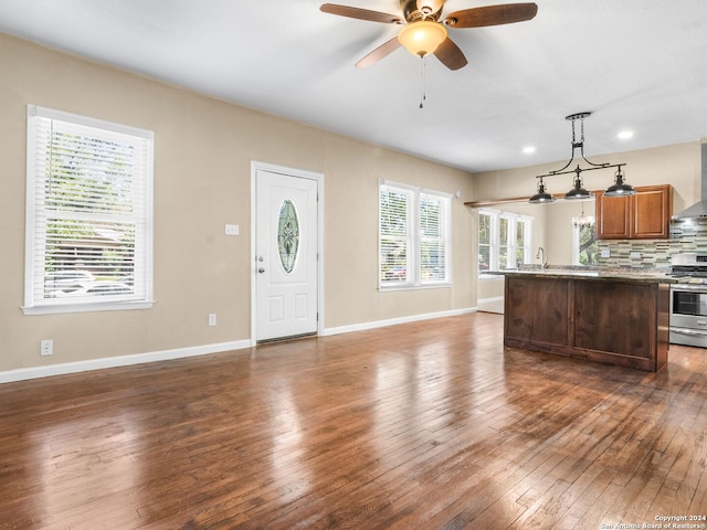 kitchen featuring dark wood-type flooring, stainless steel range oven, backsplash, and decorative light fixtures