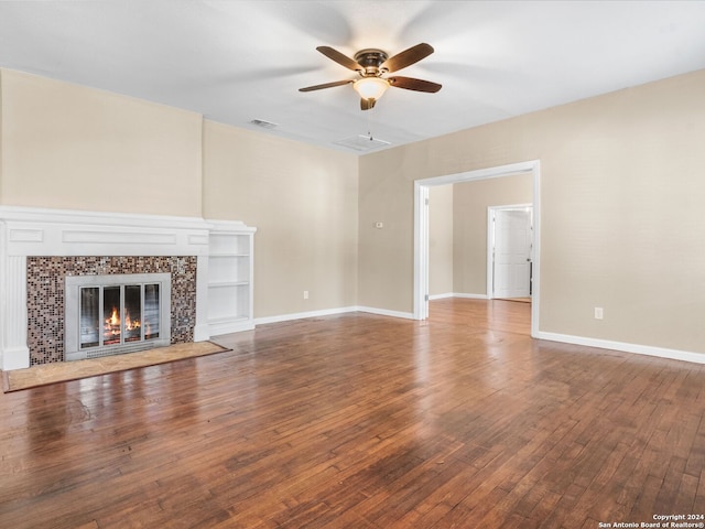 unfurnished living room featuring a tiled fireplace, hardwood / wood-style flooring, and ceiling fan