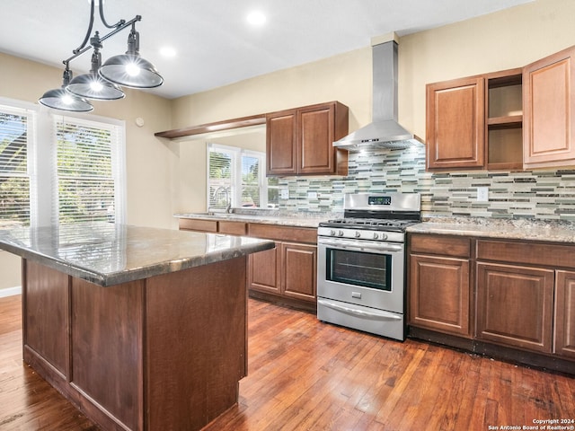 kitchen featuring dark hardwood / wood-style floors, wall chimney range hood, stainless steel gas range, and tasteful backsplash