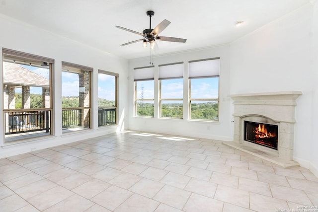 unfurnished living room featuring a fireplace, ornamental molding, ceiling fan, and light tile patterned flooring