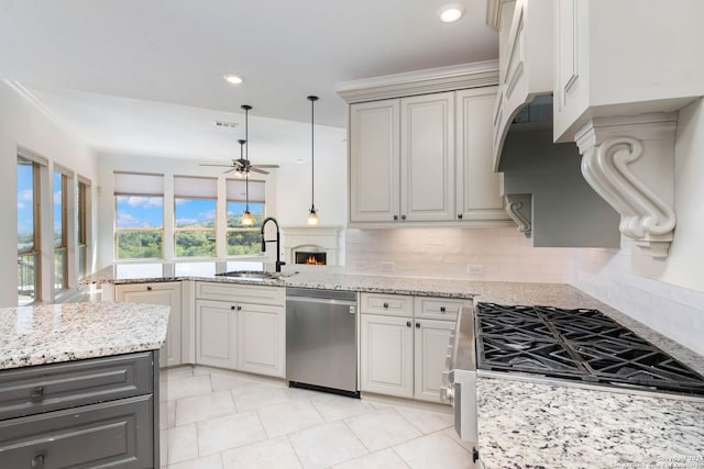 kitchen with light stone countertops, appliances with stainless steel finishes, sink, and ceiling fan