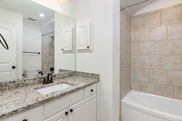 full bathroom with vanity, tiled shower / bath combo, and toilet