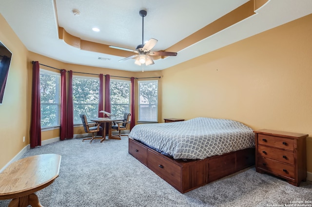 bedroom with ceiling fan, a raised ceiling, and light colored carpet