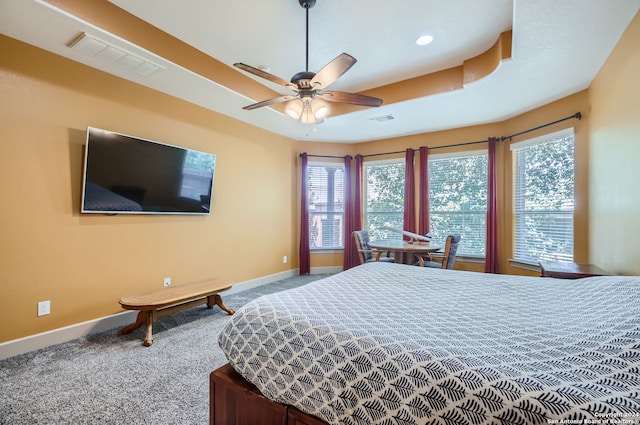 carpeted bedroom with a tray ceiling and ceiling fan