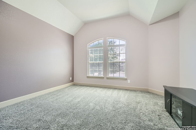 carpeted spare room featuring lofted ceiling