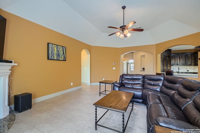 living room with a tray ceiling, vaulted ceiling, ceiling fan, and light tile patterned flooring