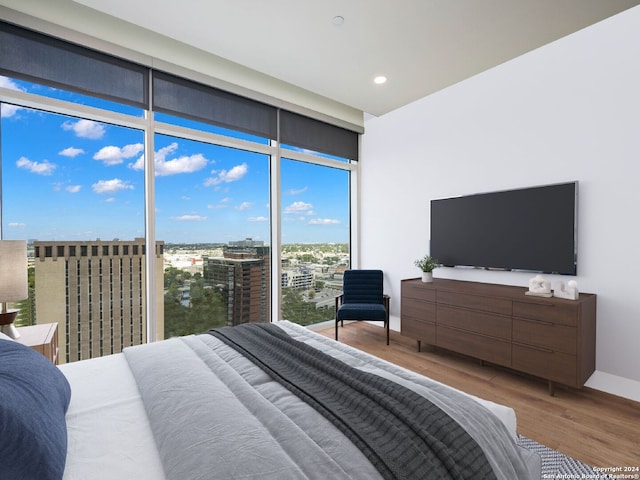 bedroom with wood-type flooring and a wall of windows