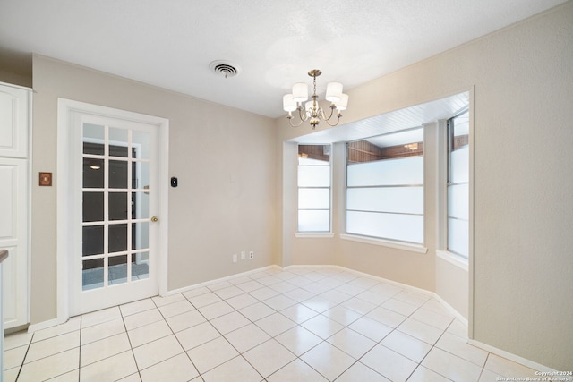 spare room with a chandelier, light tile patterned floors, visible vents, and baseboards