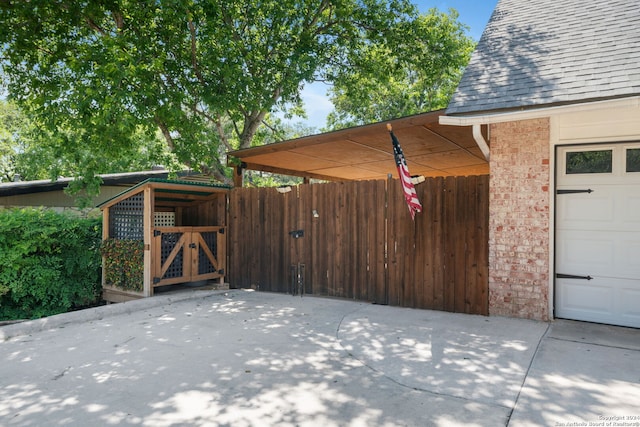 exterior space with a garage, a shingled roof, a gate, fence, and brick siding