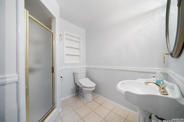 bathroom featuring toilet, a sink, baseboards, tile patterned floors, and a stall shower