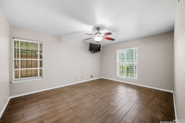 unfurnished room with ceiling fan, wood finished floors, and baseboards