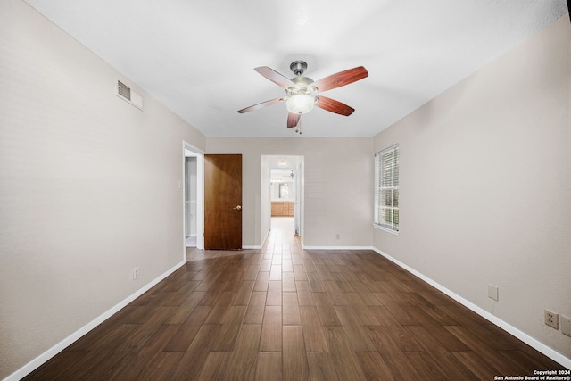 unfurnished room with dark wood-type flooring, a ceiling fan, visible vents, and baseboards