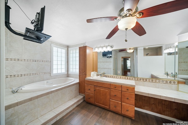 bathroom featuring tiled bath, ceiling fan, hardwood / wood-style floors, and vanity