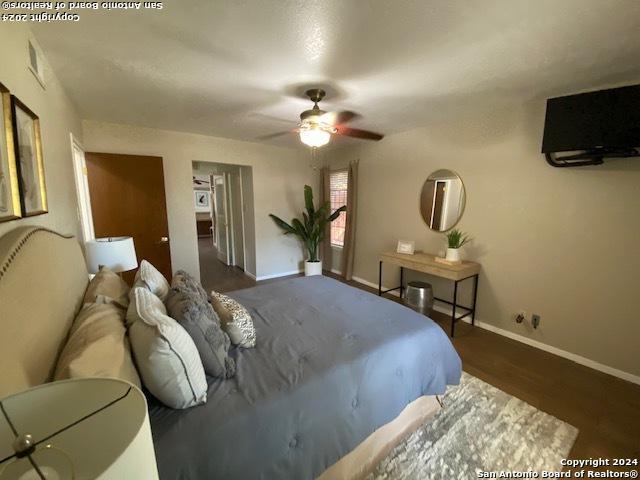 bedroom with ceiling fan, dark wood-style flooring, and baseboards