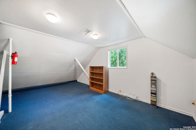 bonus room with dark colored carpet and lofted ceiling