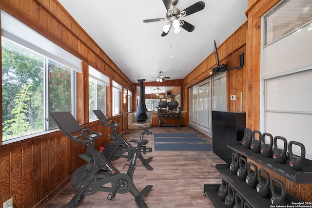 workout room featuring wood walls, ceiling fan, and dark wood-type flooring