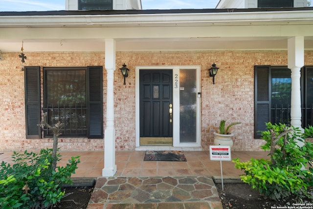 doorway to property featuring brick siding and a porch