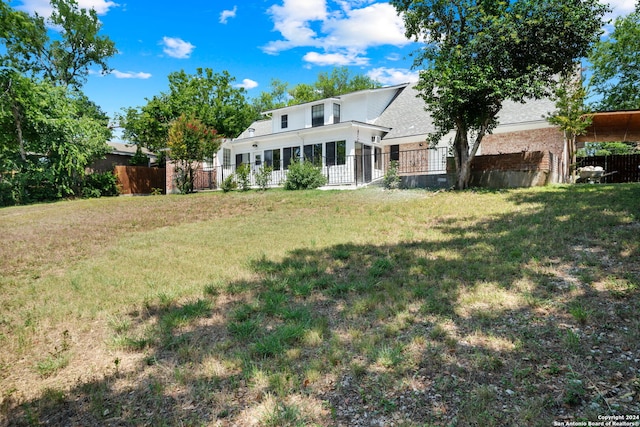 view of front of home featuring brick siding, a front lawn, fence, and a sunroom