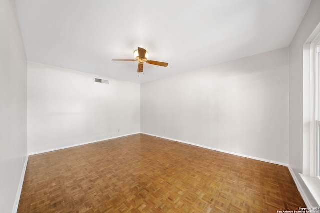 unfurnished room featuring ceiling fan, parquet floors, and a healthy amount of sunlight