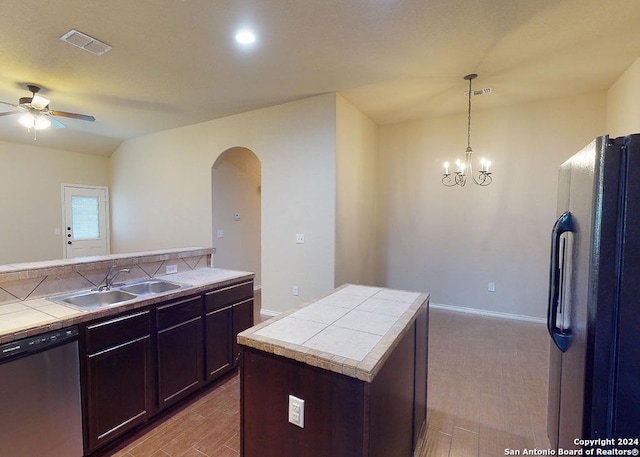 kitchen with stainless steel dishwasher, ceiling fan with notable chandelier, sink, a center island, and black refrigerator