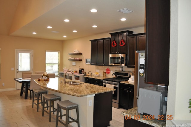 kitchen featuring a kitchen island with sink, a breakfast bar, a sink, visible vents, and appliances with stainless steel finishes