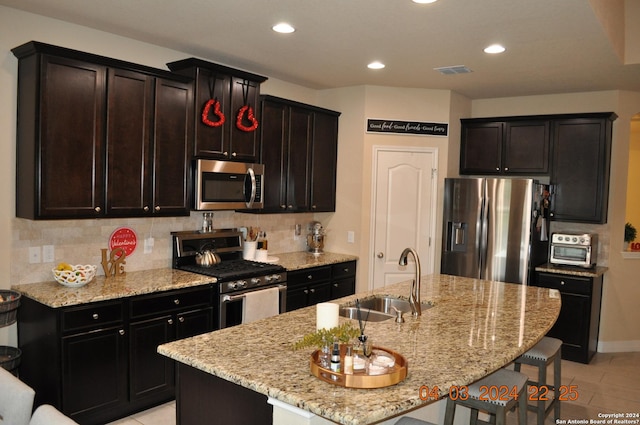 kitchen featuring stainless steel appliances, a breakfast bar, a sink, and a kitchen island with sink