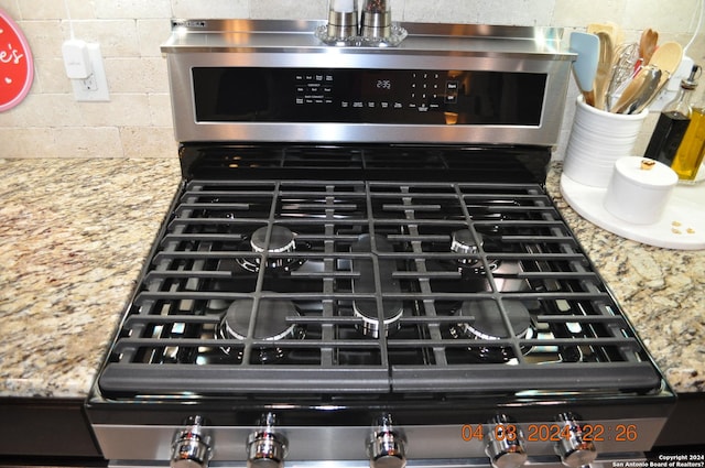 interior details featuring light stone counters and stainless steel range with gas stovetop