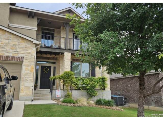 view of front facade featuring a balcony, central AC, and a front lawn