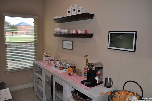 bar with plenty of natural light, baseboards, and light tile patterned floors