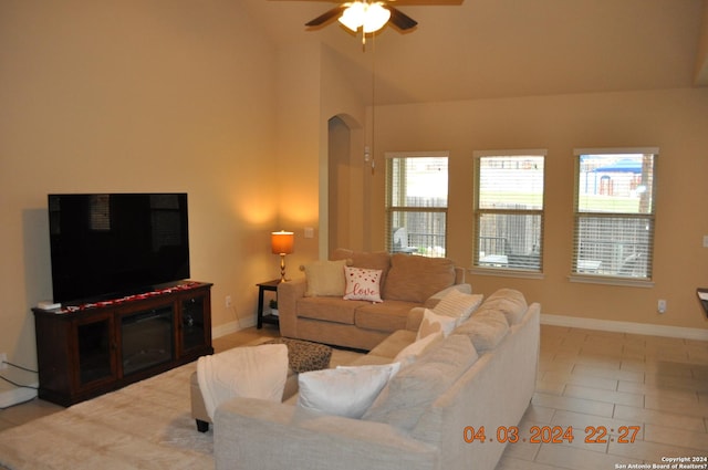 living area featuring light tile patterned floors, baseboards, vaulted ceiling, and a ceiling fan