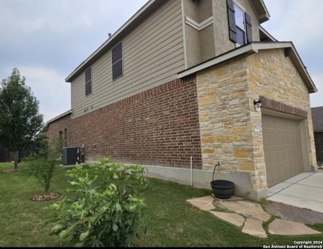 view of side of home featuring a garage, a lawn, stone siding, central air condition unit, and brick siding