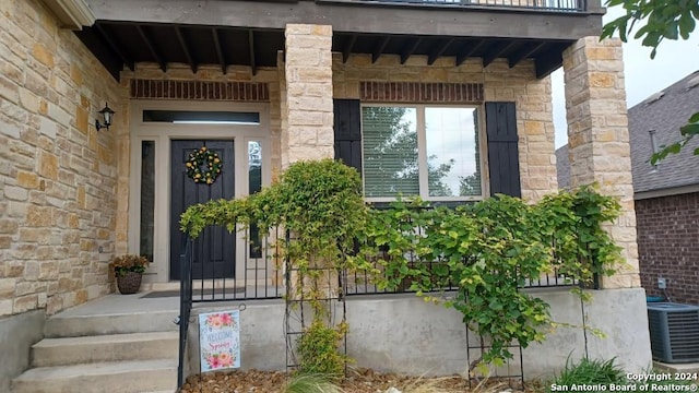 doorway to property featuring stone siding and central AC unit